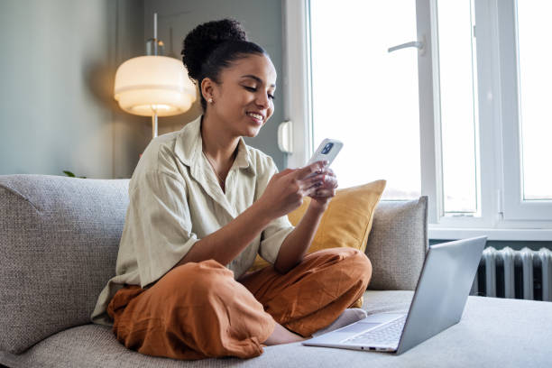 Young woman with styled hair holding a card and phone, sitting cross-legged with a backpack